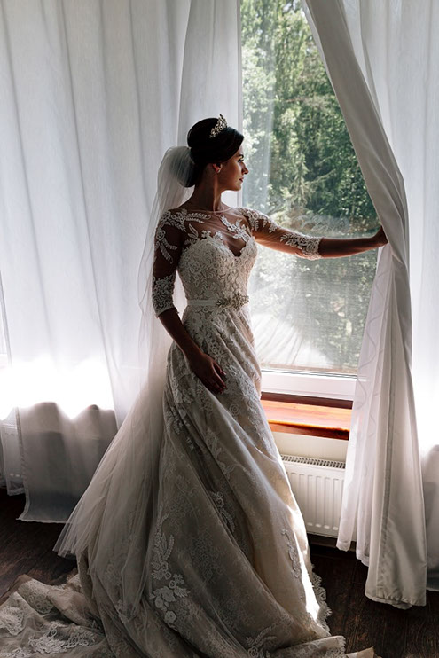 Невеста смотрит в окно перед церемонией регистрации.
