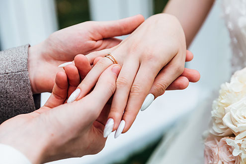 Жених одевает невесте кольцо на палец.
