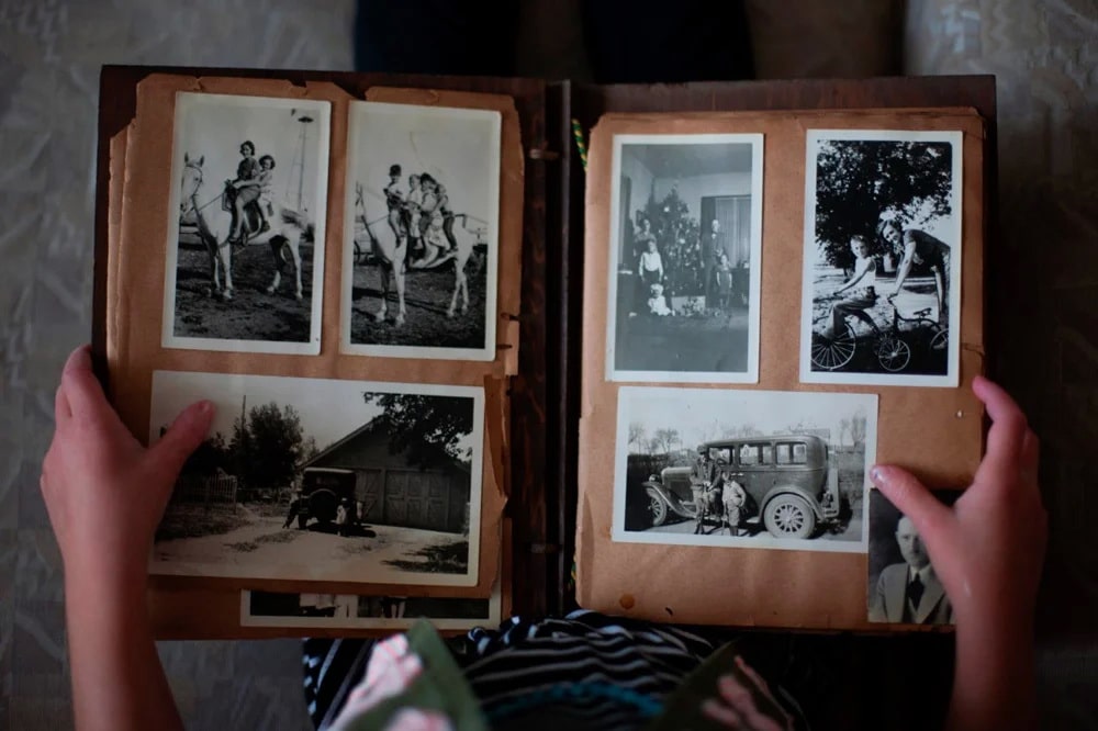 Старый фотоальбом с вклеными на уголки черно-белыми фотографиями.
